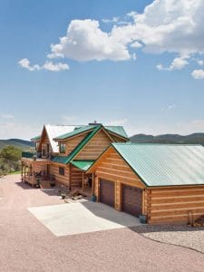 green roofs on light wood log cabin with blue sky background