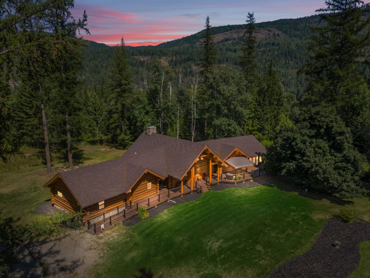 drone view of log cabin from above with mountains and sunset in background