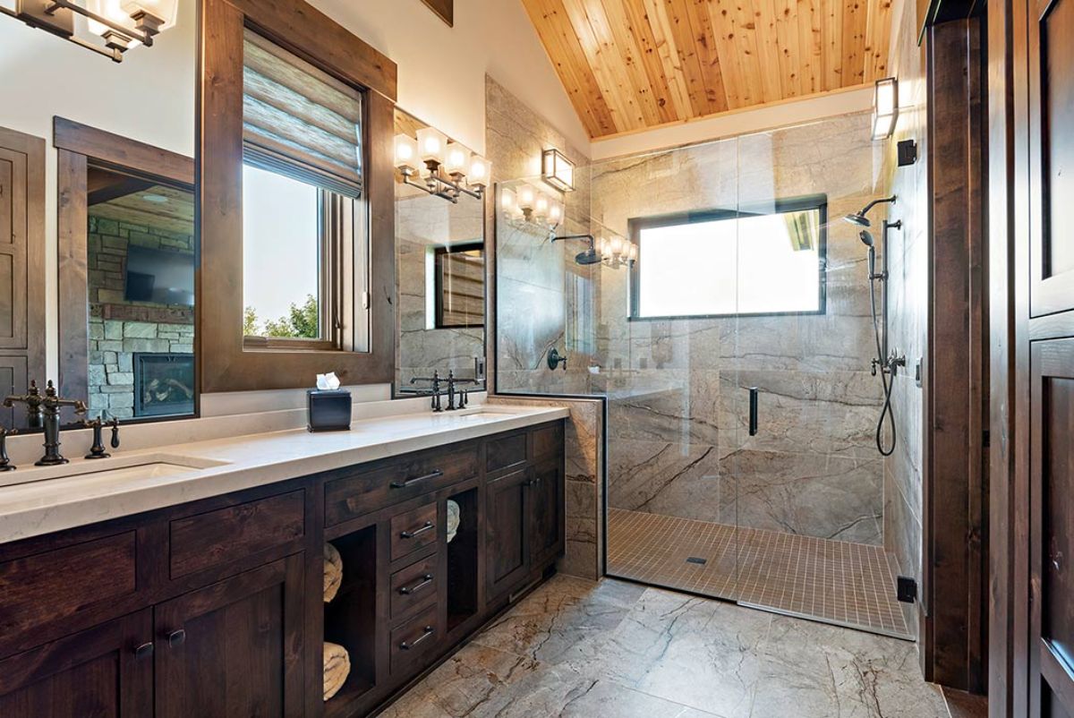 master bathroom with tile shower on back wall with glass door and dark wood cabinets on left