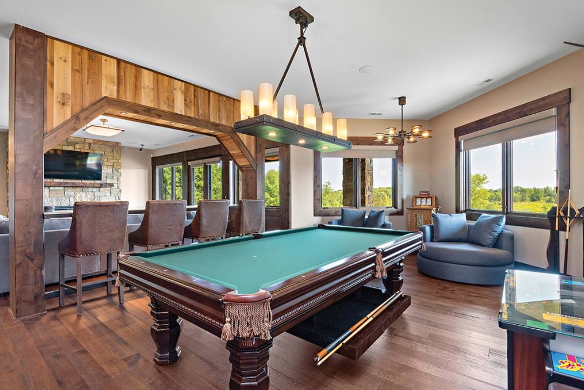 green topped pool table with blue sofa in background and long chandelier above