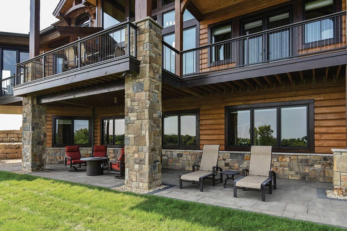 back of log cabin showing covered patio with lounge chairs and bistro set