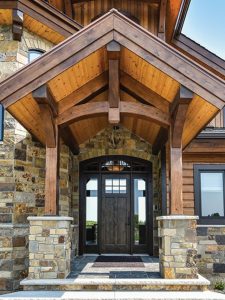 front door to cabin with stone columns and wall