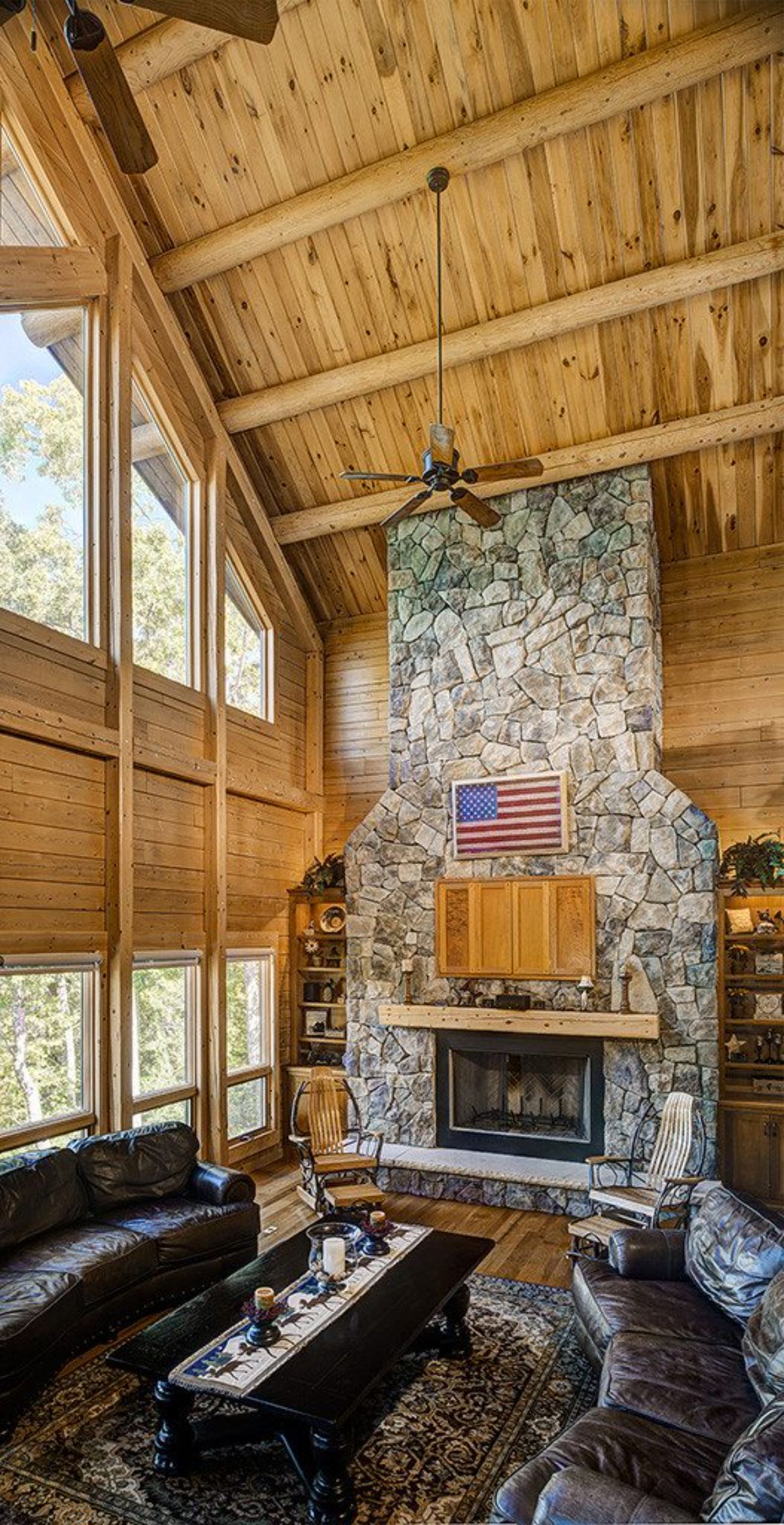 stone fireplace with wood mantle and American flag decor against light wood wall