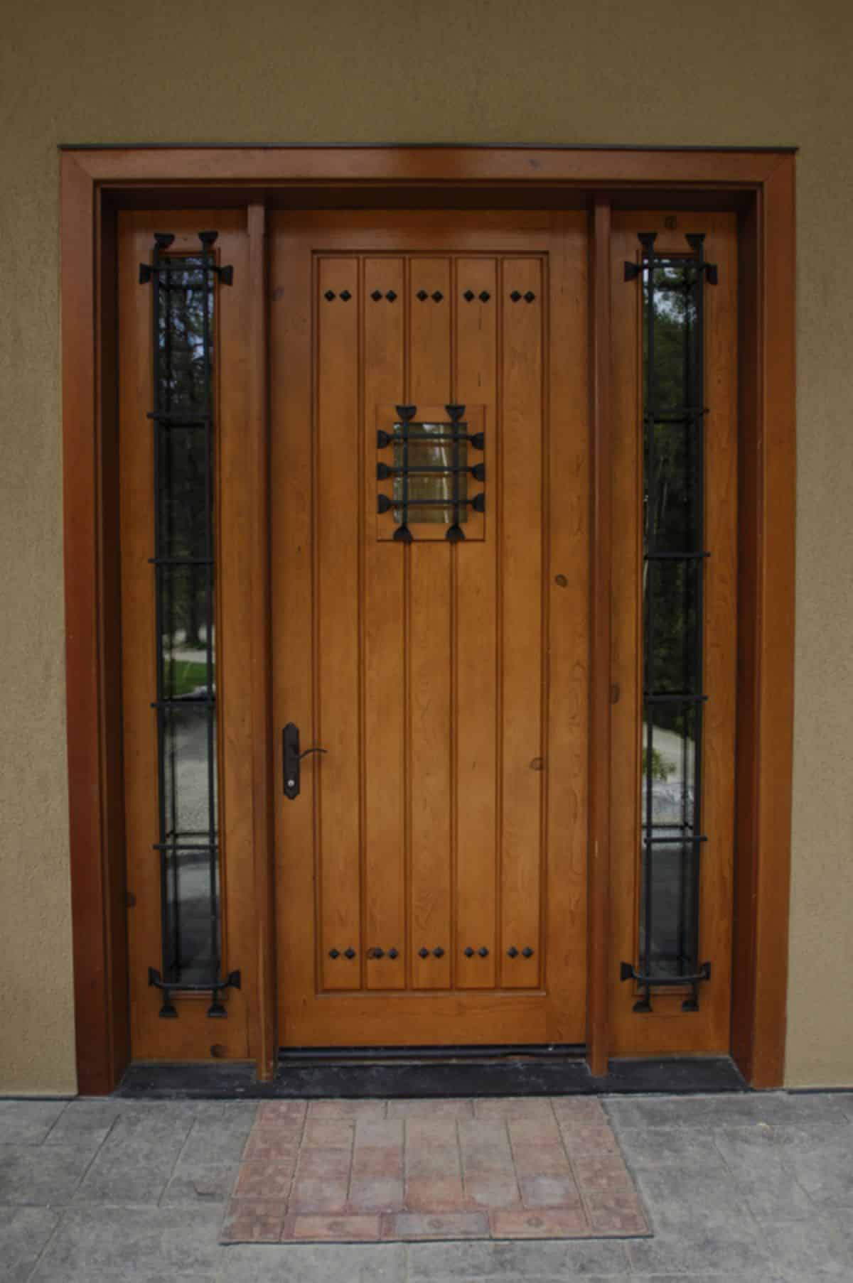 wood door with glass panels on sides and wrought iron additions