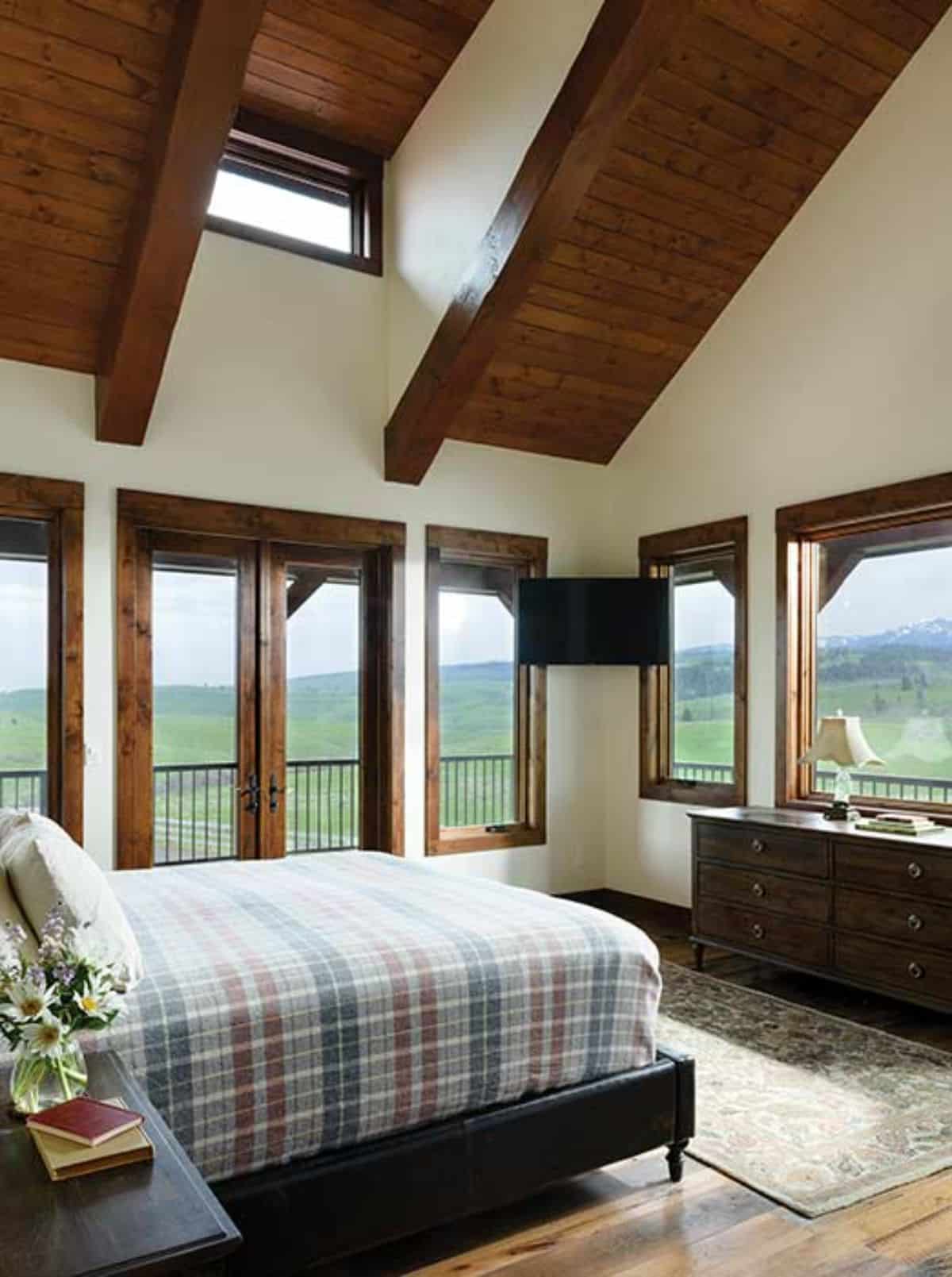 striped white and blue bedding on bed under skylight in room with white walls and exposed wood beam