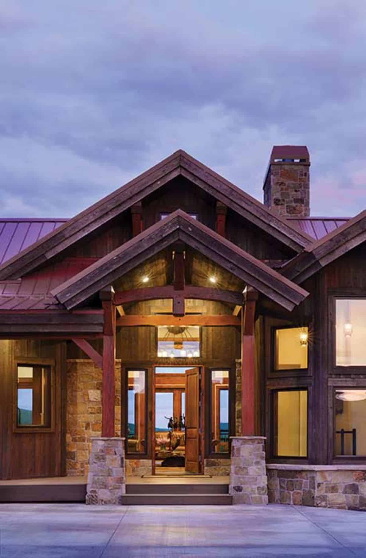 front door to cabin with red roof and stone columns on porch