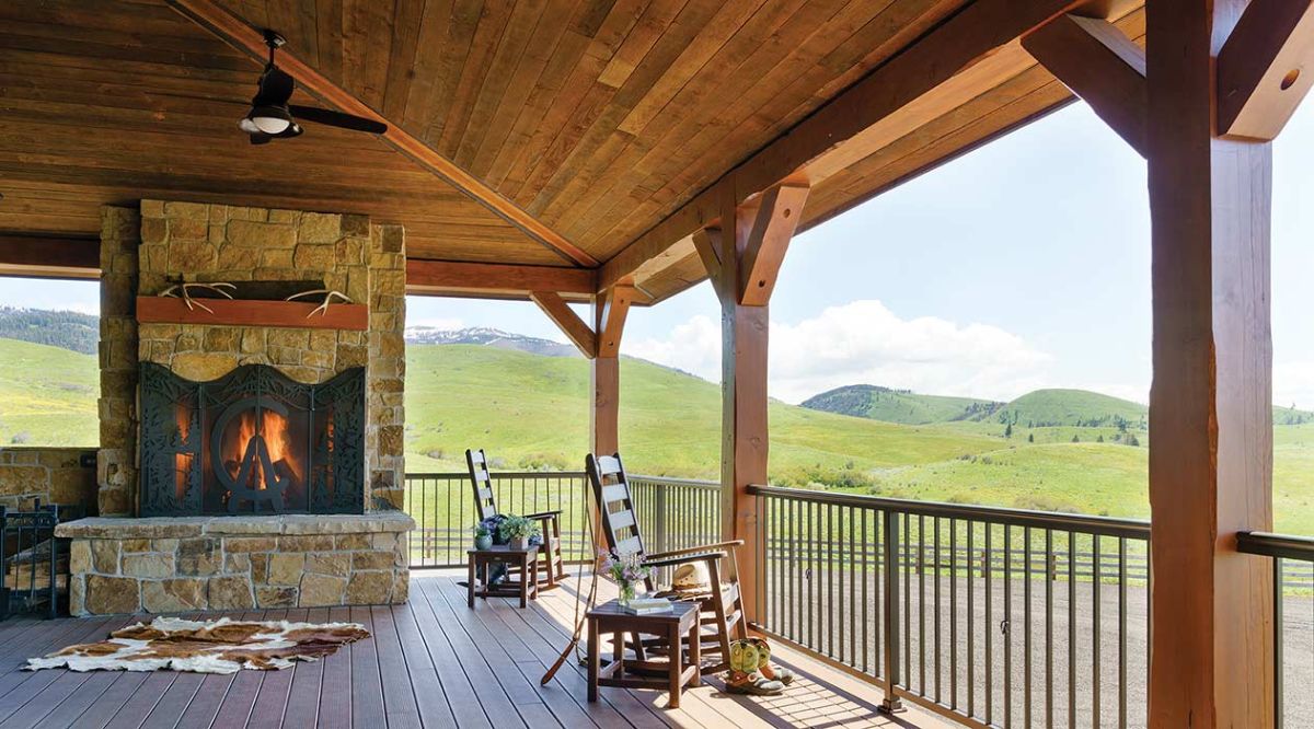 fireplace under roof of small porch on cabin with wood railing