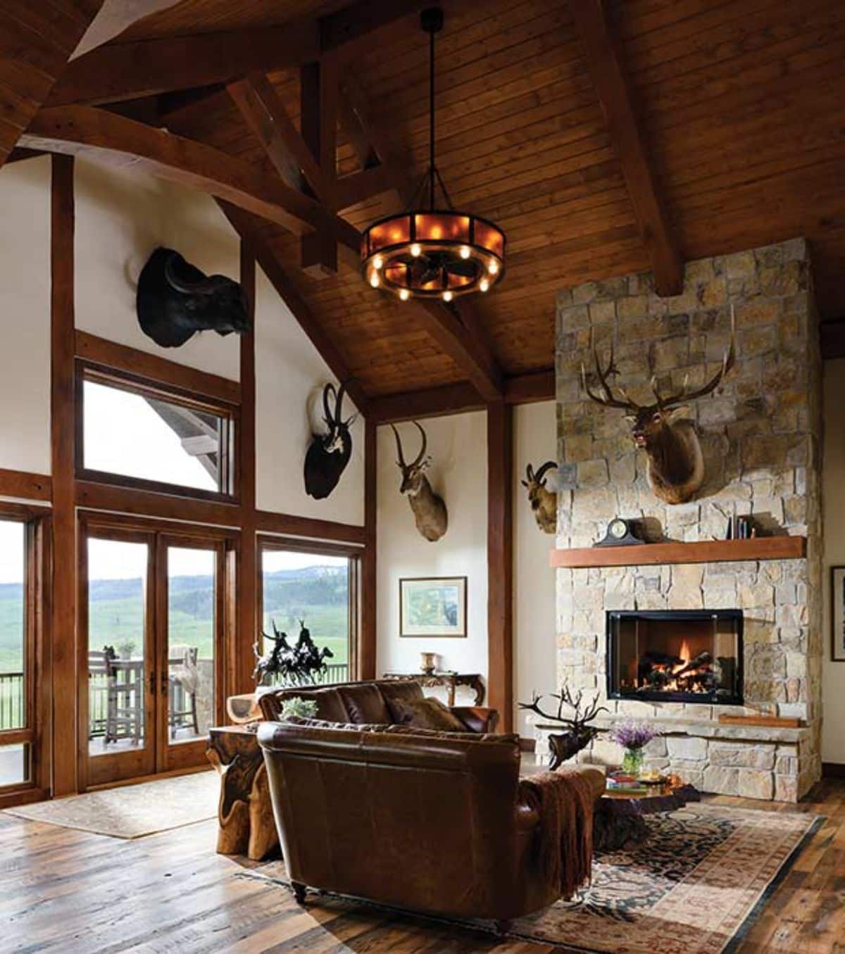 fireplace on back wall of log cabin with wall of windows on left