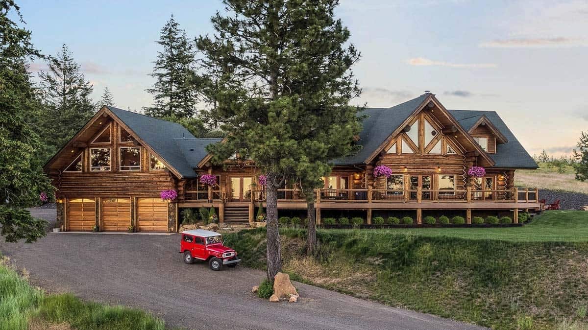 red jeep on driveway in front of large cabin with three car garage