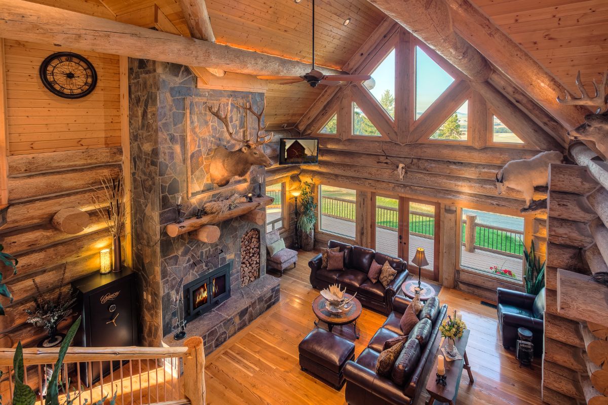 view down into log cabin living room with stone fireplace on right
