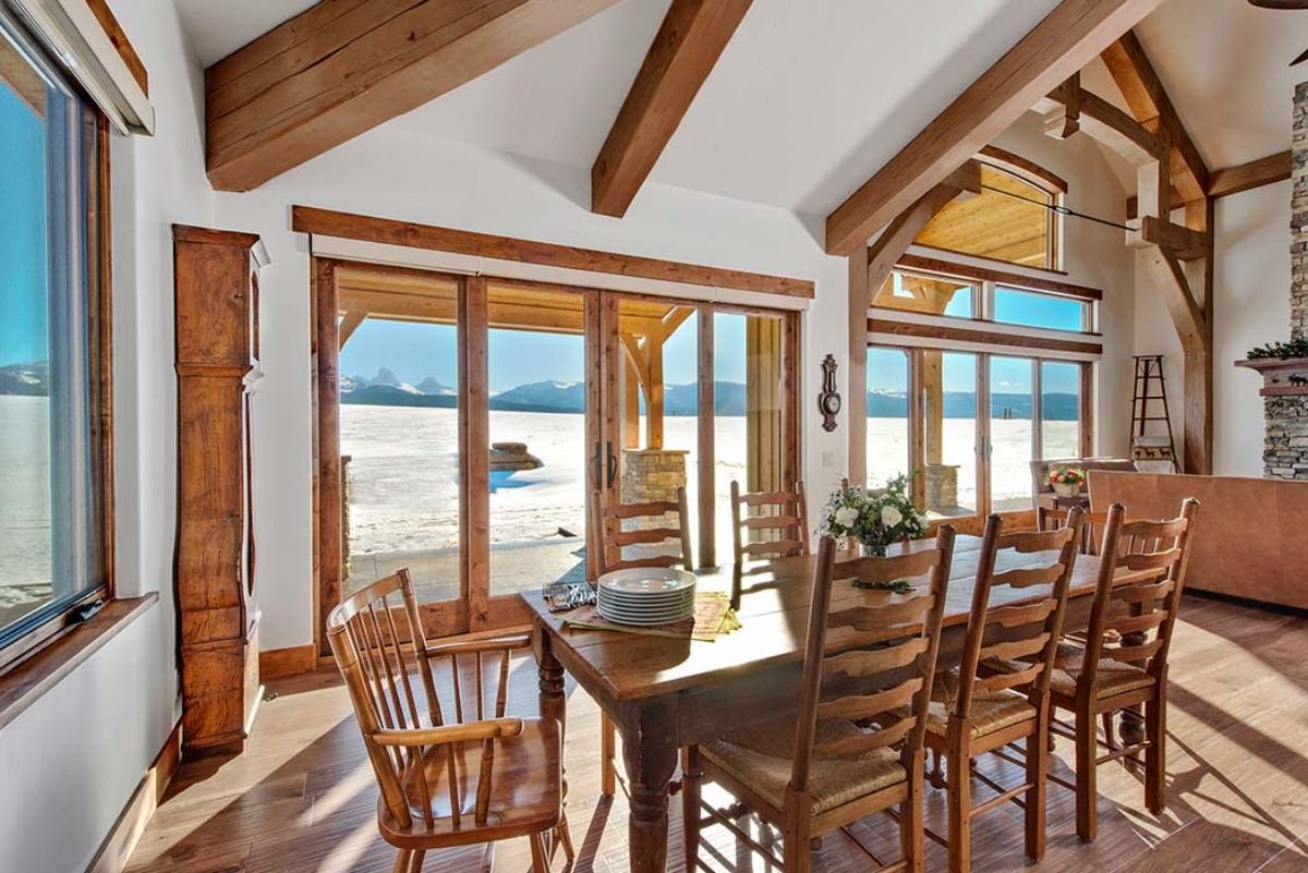 wood table with high back chairs in dining nook with white walls and picture window overlooking property