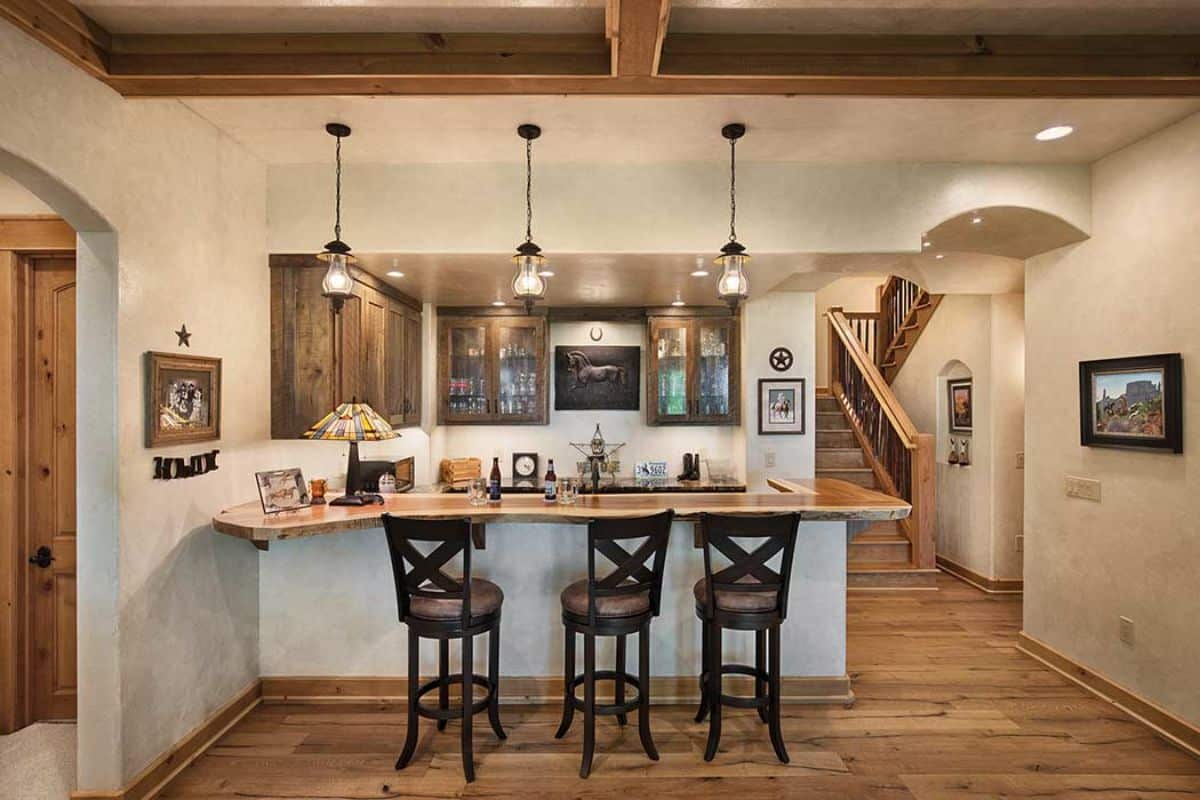white island with high back black chairs with cushions in front of log cabin kitchen