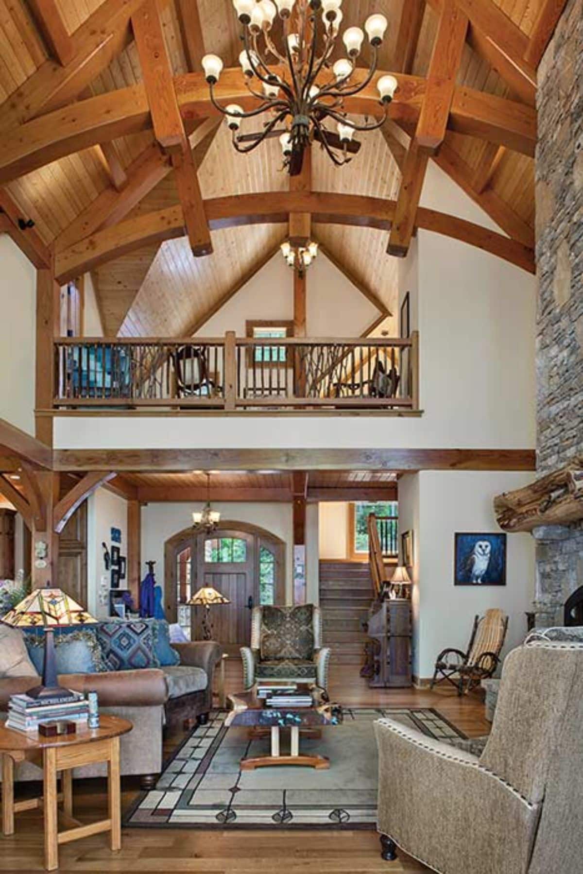 living room of cabin with stone fireplace on right and gray seating on left with loft above in background