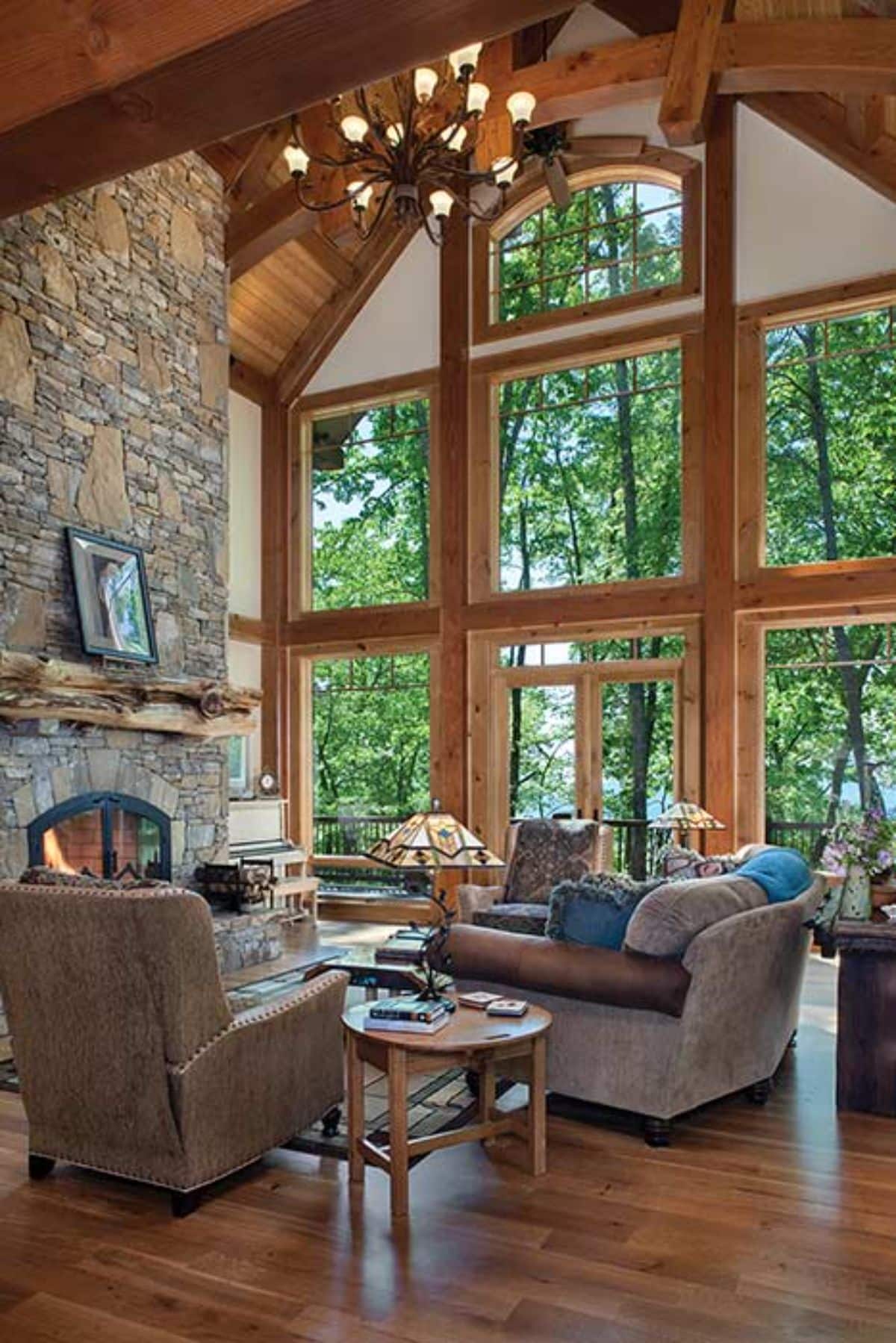 light brown seating in front of fireplace on left with wall of windows on the right