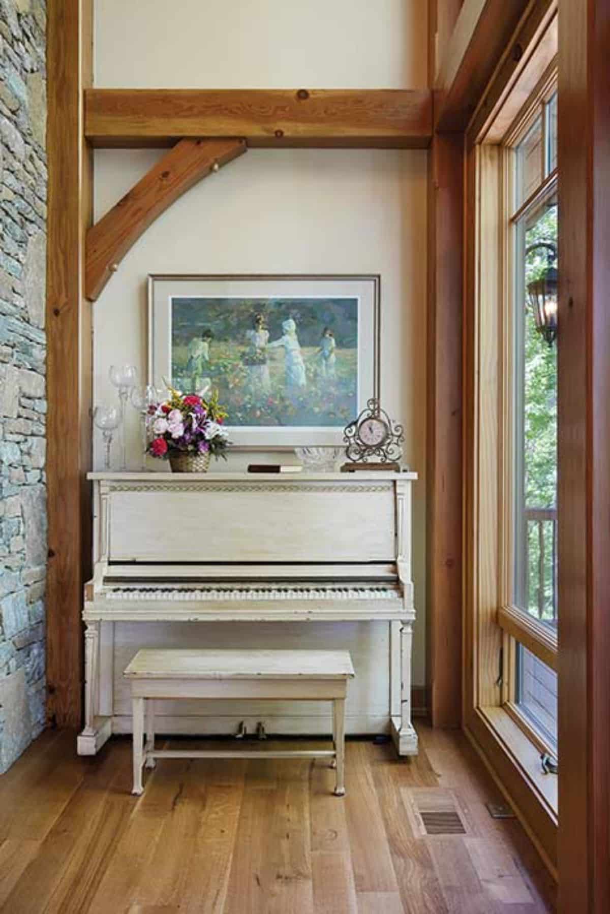 white upright piano against white wall with windows to the right