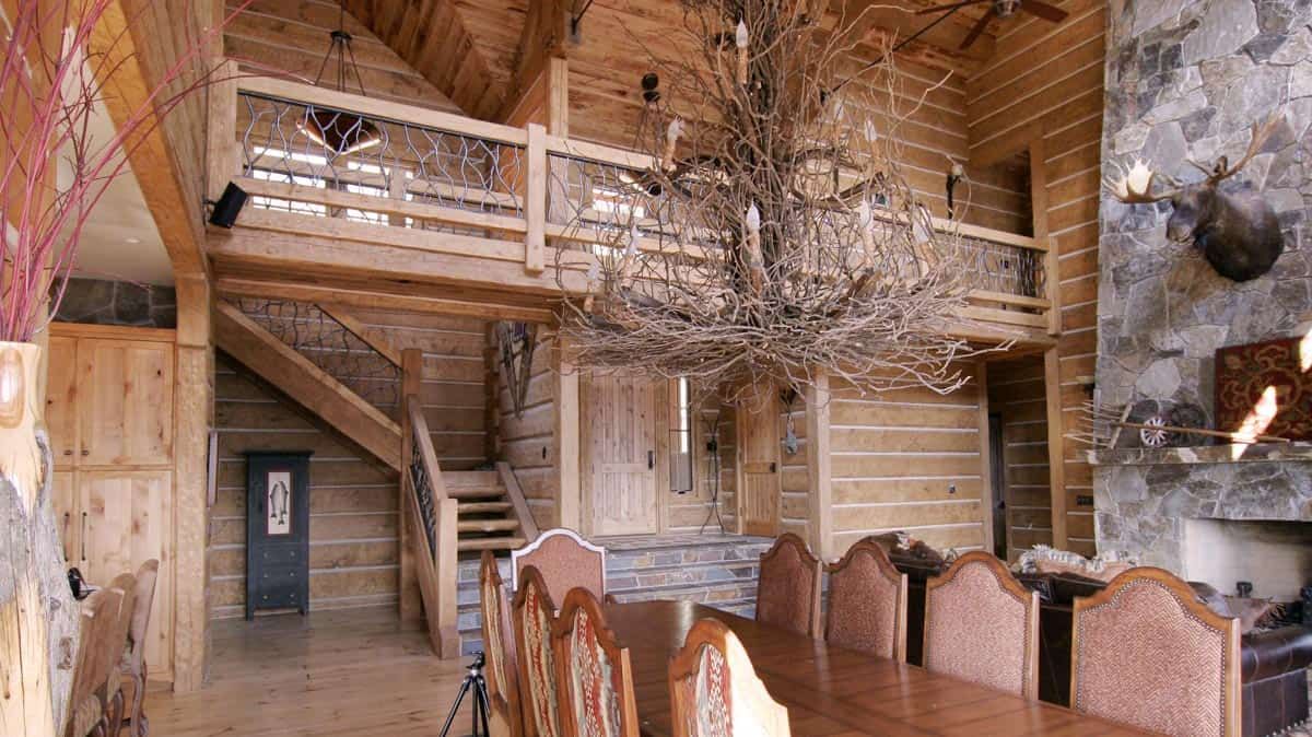 light wood interior of cabin with giant antler chandelier over dining table