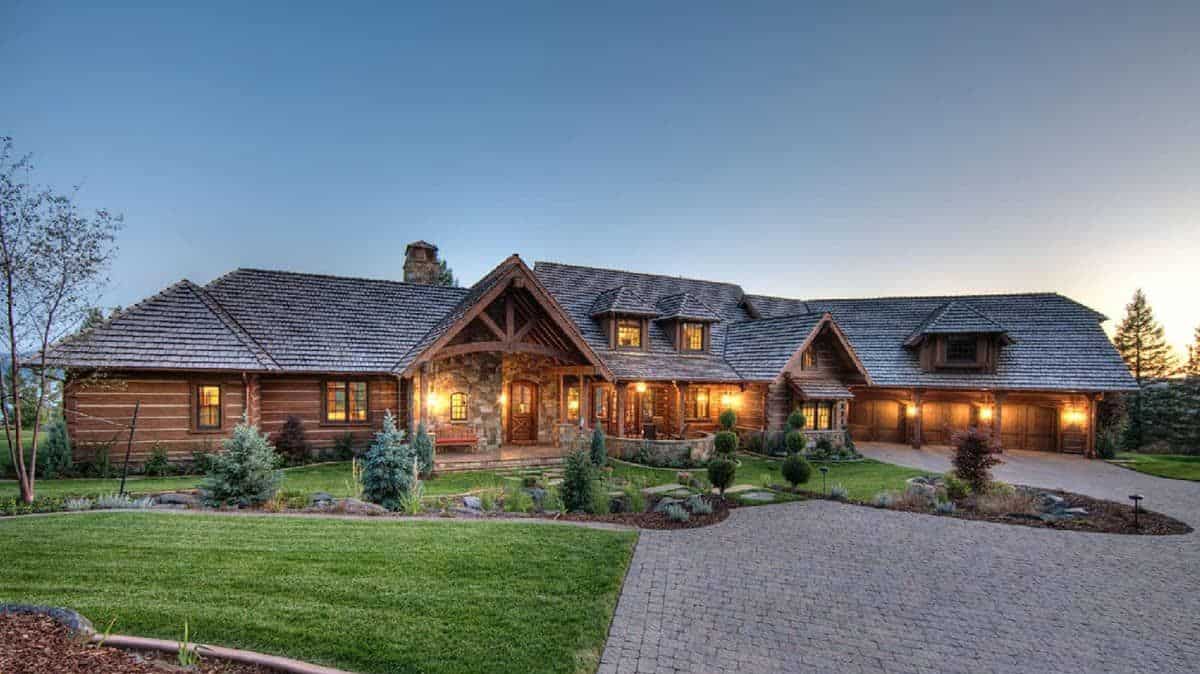 drive leading to front of log cabin with sprawling floor plan and sunset in the background