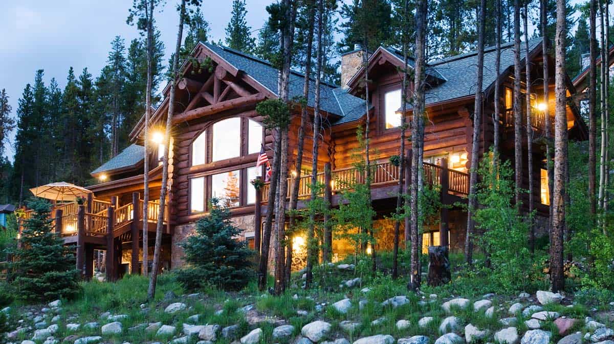 great room windows lit after sunset on log cabin