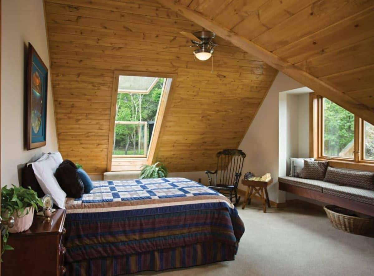 loft bedroom with arched ceilings and bed with quilt on left side