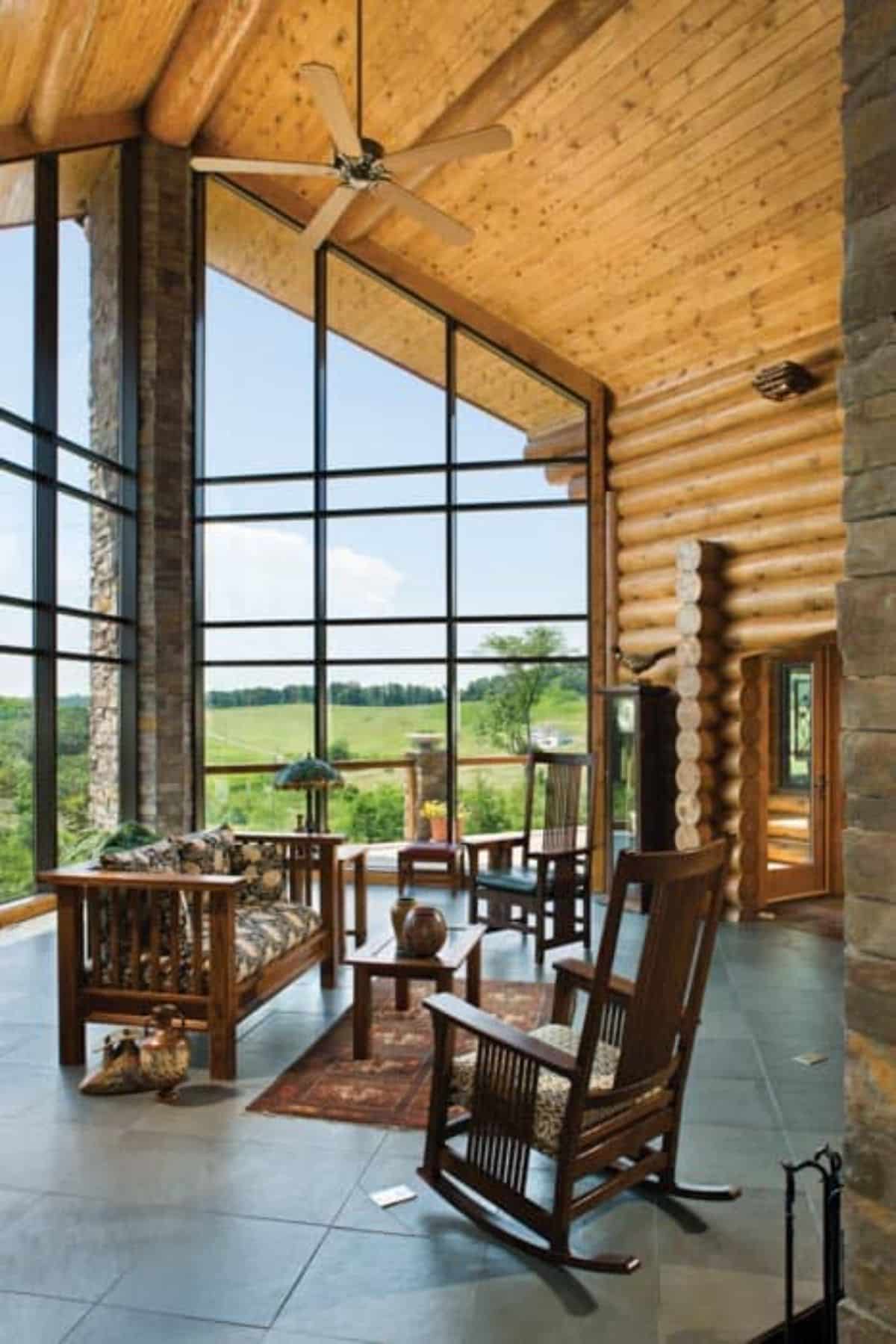 great room wall of windows with wood sofa and chairs on rug