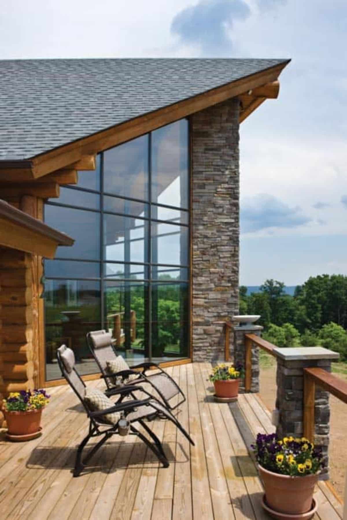 adirondack chairs on open porch by wall of windows