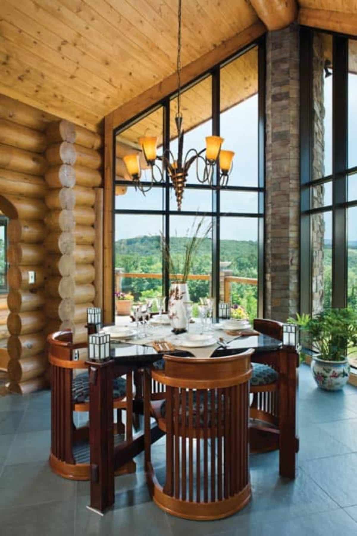 round table under chandelier with wall of windows on right