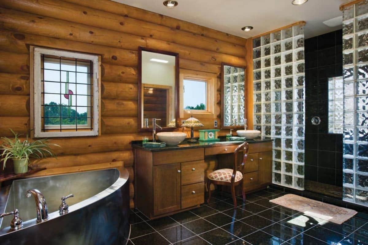 soaking bathtub in corner of log cabin bathroom with glass blocks on right