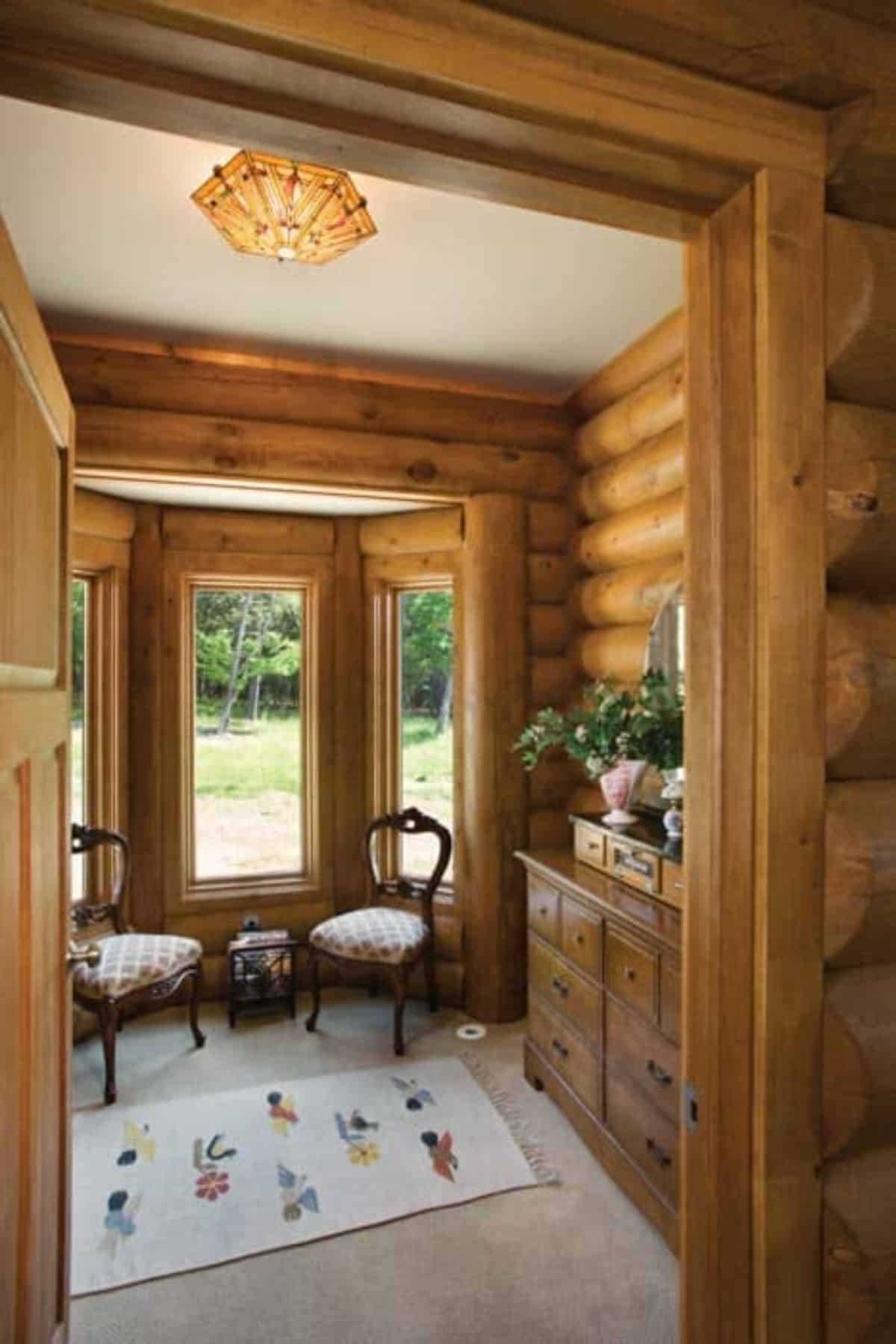 chairs in front of bay window with log walls