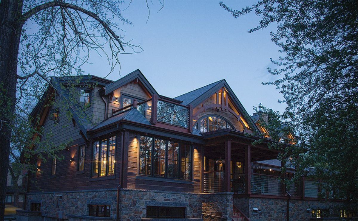 back of log cabin with wall of windows above stone foundation