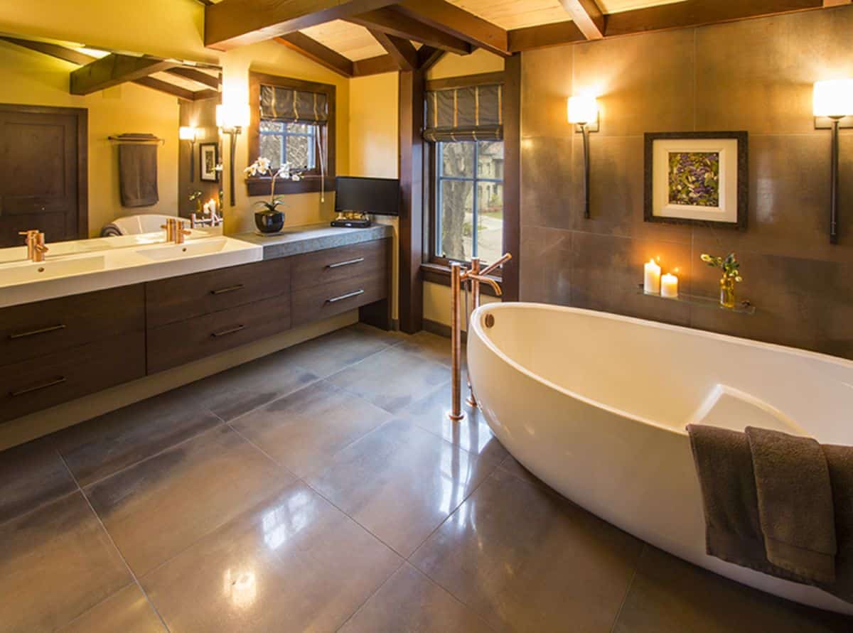 white soaking bathtub against right wall of master bathroom with dark wood accents