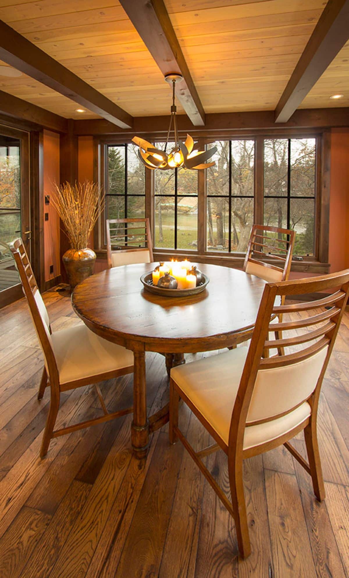 wooden round table with high back wood chairs and wall of windows in background