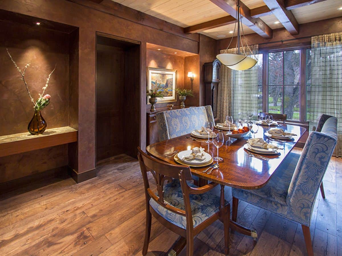 dining table with glass doors in background and light blue upholstery on chairs