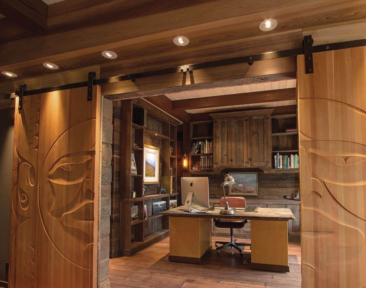 view through sliding doors into home office with desk in center and cabinets all around