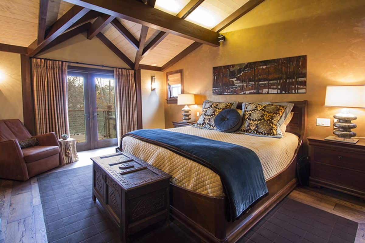 blue blanket on end of bed in master bedroom with french doors to deck on left