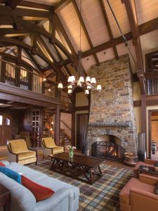 stone fireplace on right wall of living room with wood table and yellow chairs on left