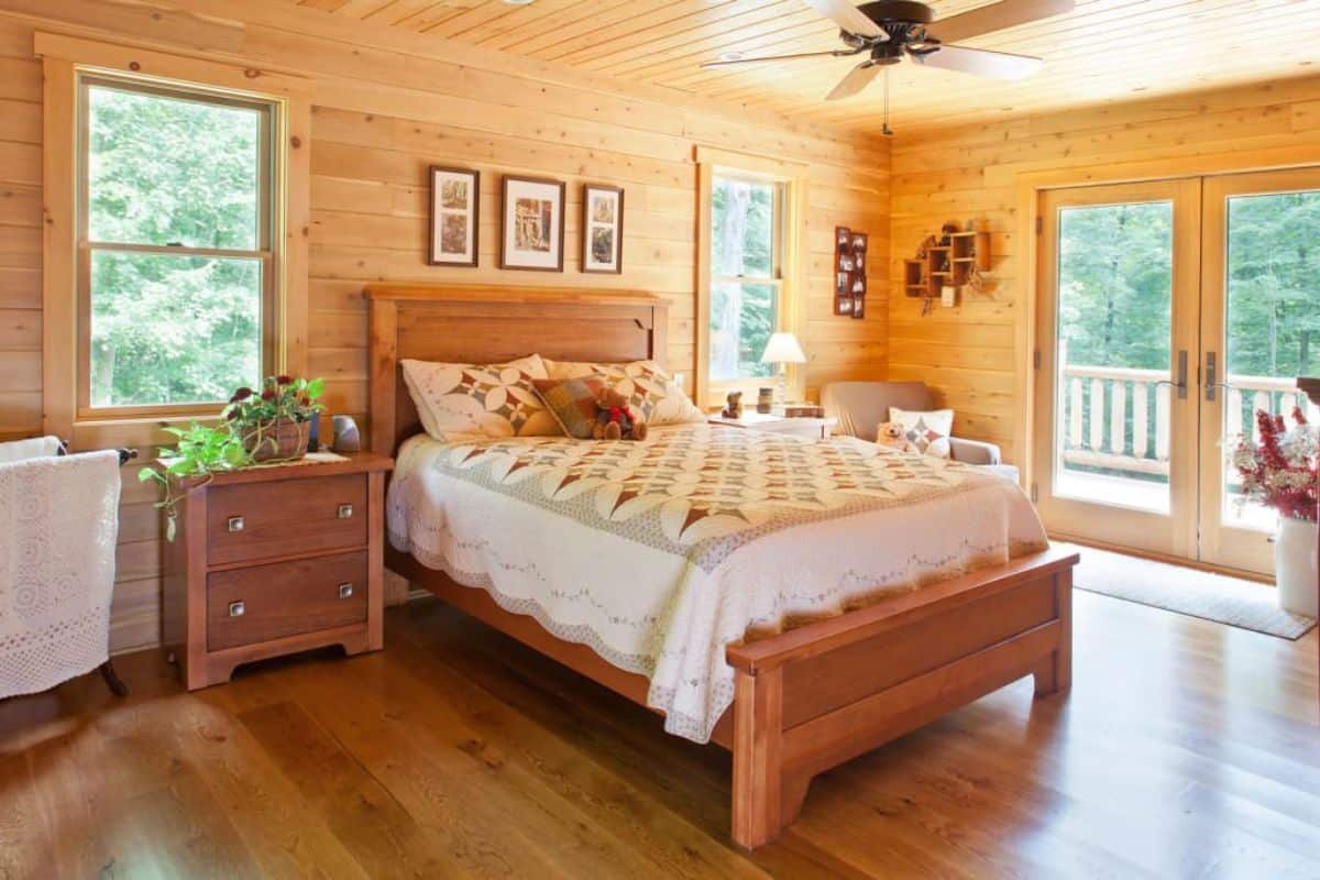 light wood frame on bed with white bedding in log cabin bedroom