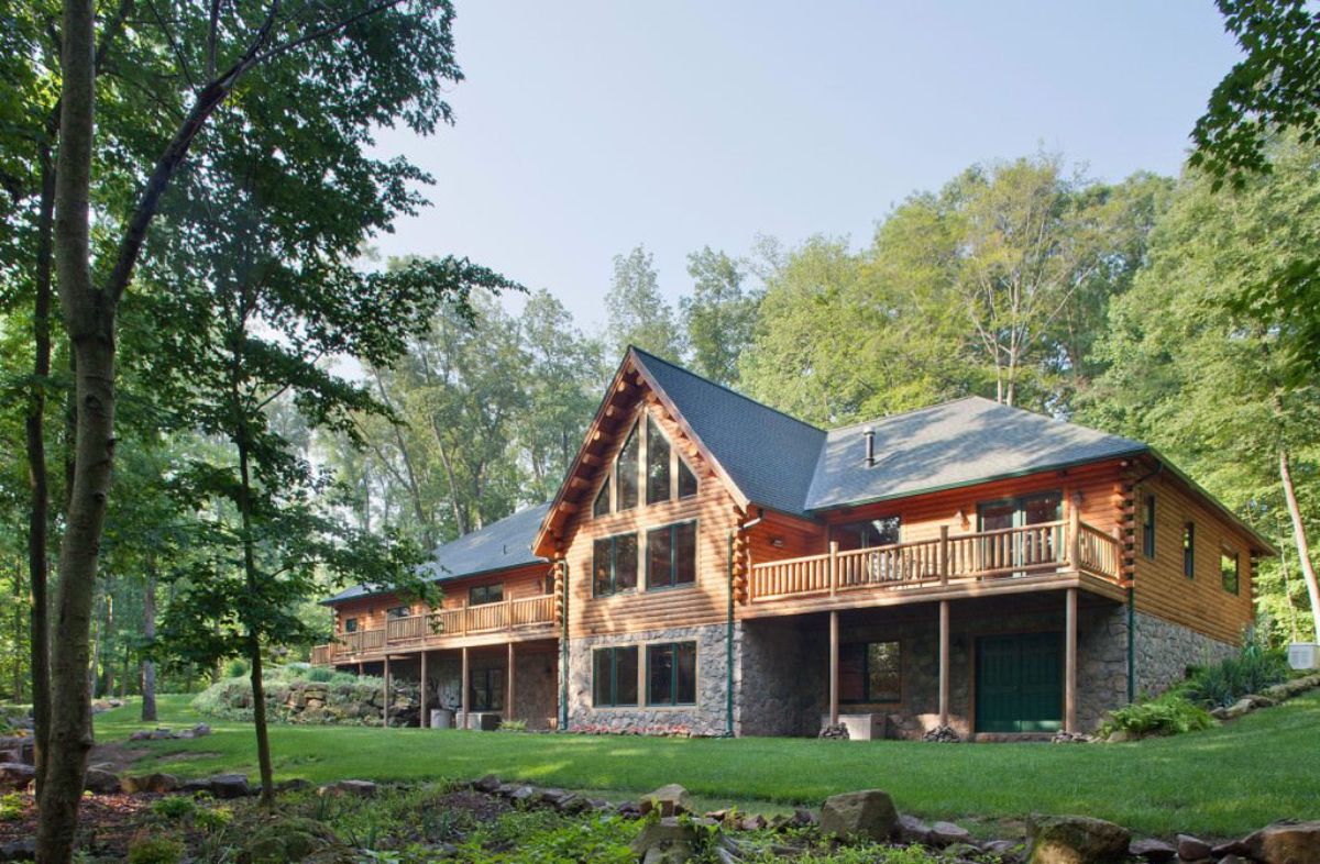 back of log cabin with great room in center with wall of windows