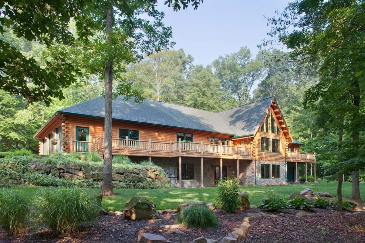 back of log cabin with second floor open deck and stone foundation