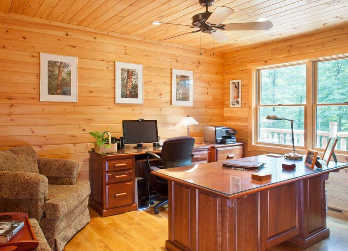 medium stain wood desk in cabin office with brown chair on left of desk