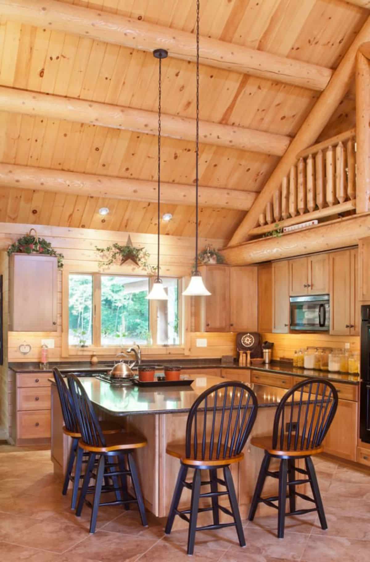 kitchen island with bar and high back stools with light wood cabinets