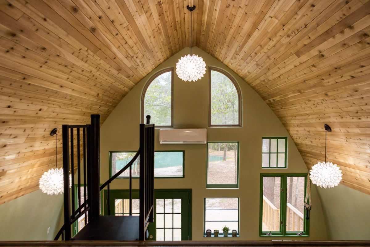 black spiral staircase on left of loft with windows of back wall visible in background