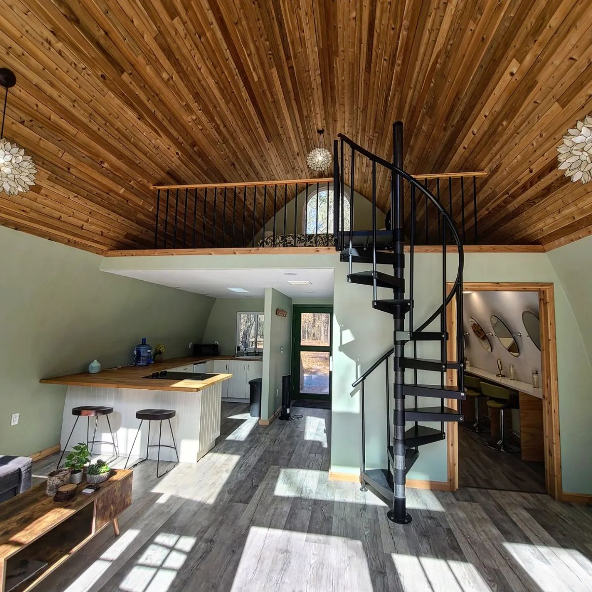 view into cabin with sprial staircase in center of room and kitchen on left