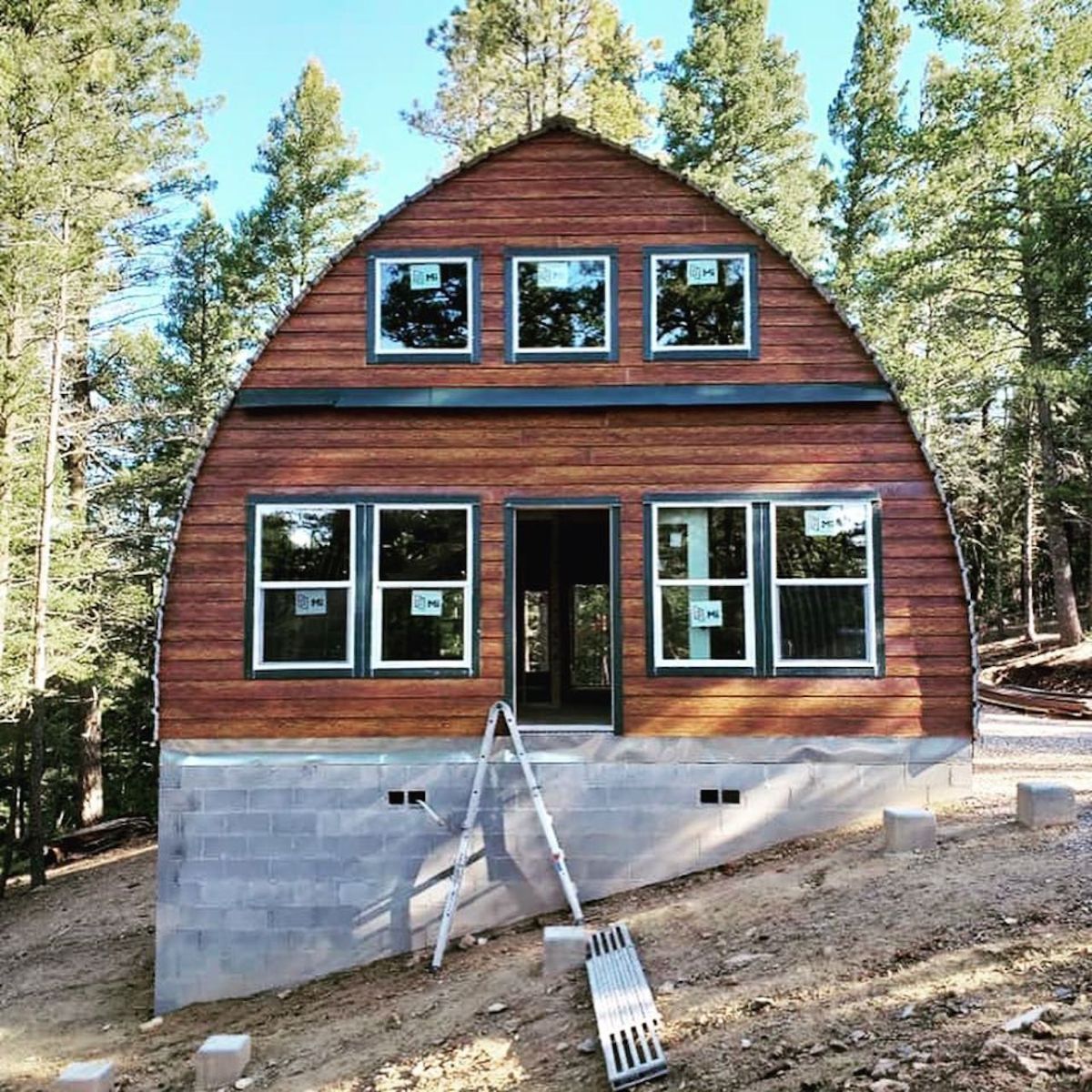 red stain wood siding on front of arched cabin