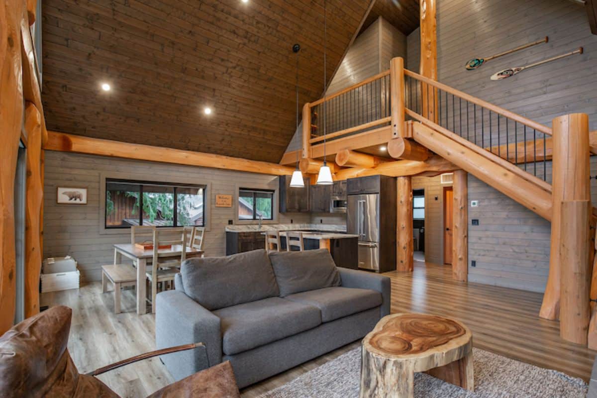 gray loveseat in center of living room with kitchen in background