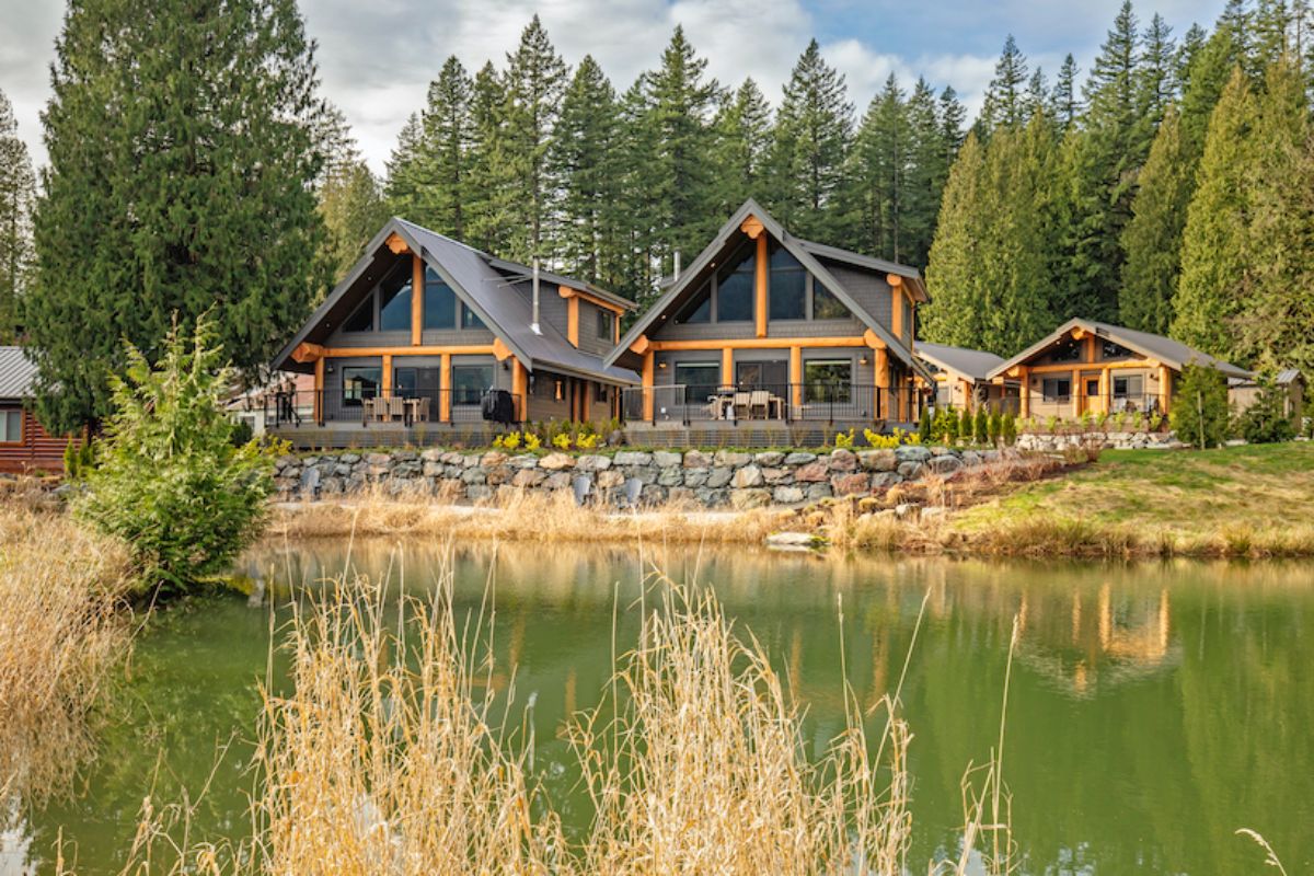 view of two gray cabins from across pond