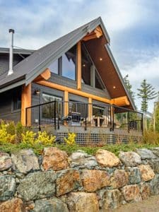 wood and gray siding on cabin with wrought iron railing on edge by rock hill