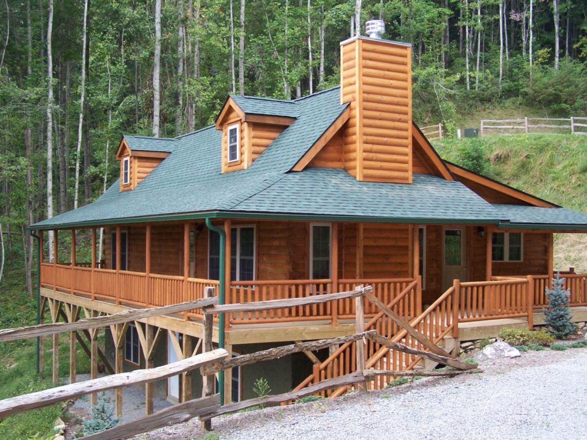 side of cabin with green roof on side of sloping hill