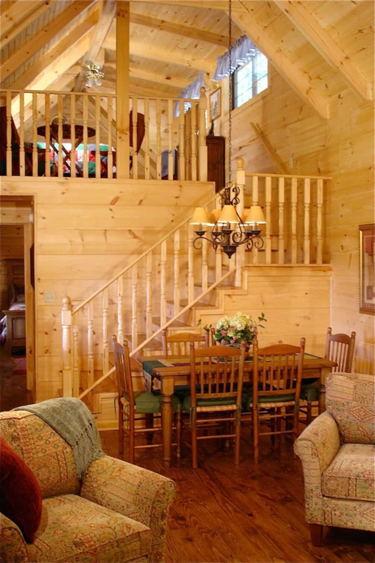 stairs to loft behind traditional dining table with olive green accents