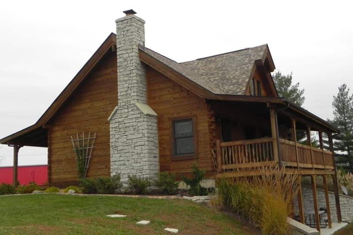 side of cabin with stone fireplace in middle of wall