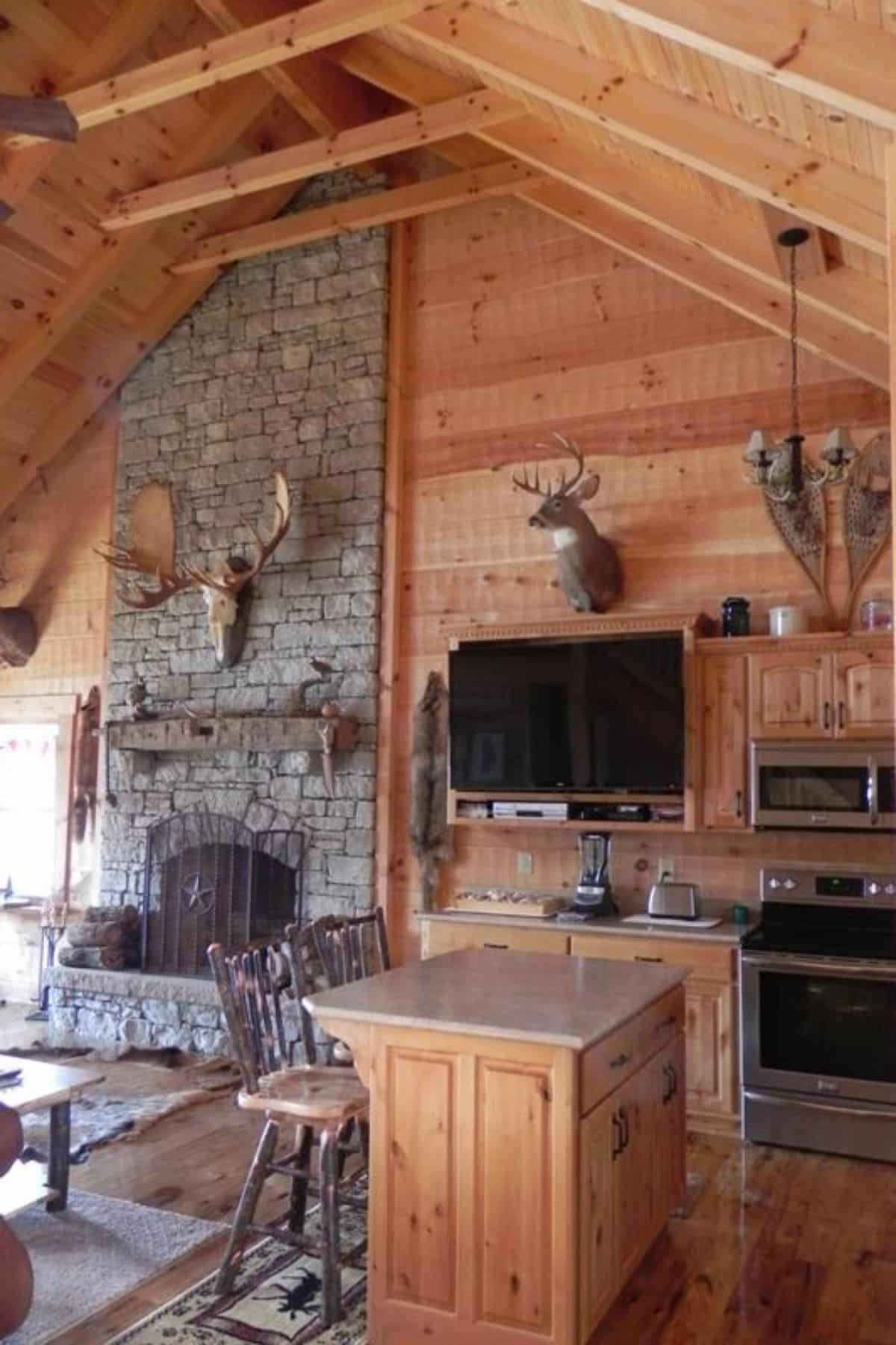 fireplace on far wall of cabin living room with TV mounted next to it
